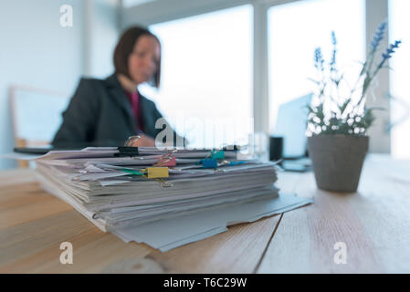 Occupé businesswoman doing paperwork in office au bureau rempli de papiers et de documentation Banque D'Images