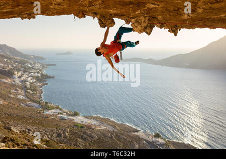 Caucasian male rock climber sur route difficile qui va de pair dans la grotte au plafond Banque D'Images