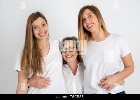 Studio session de portrait avec la mère et ses deux soeurs jumelles vêtus de t-shirts blanc et bleu jeans en cuivre avec fond clair. Banque D'Images
