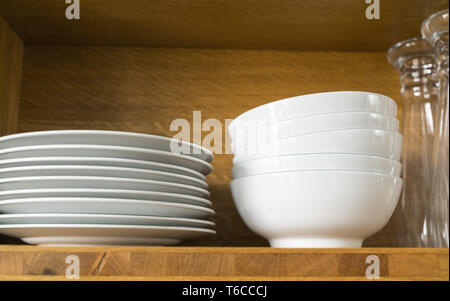 Des plats et des verres blancs dans une étagère de cuisine