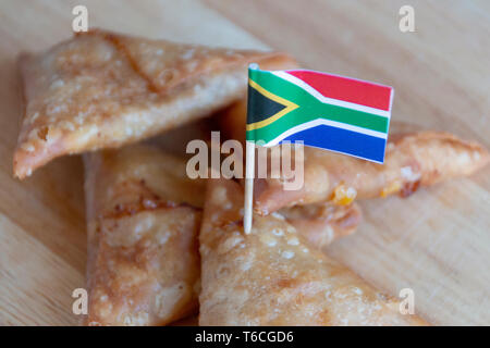 Une vue en gros plan d'un tas de samosas de l'Afrique du Sud avec un petit drapeau de l'Afrique du Sud dans l'un conner Banque D'Images