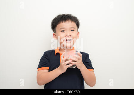 Jeune garçon de boire du lait au chocolat isolé sur fond de mur blanc. Banque D'Images