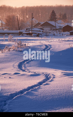 Sentier des traces dans la neige, dans l'Altaï russe village en hiver à l'heure du matin Banque D'Images