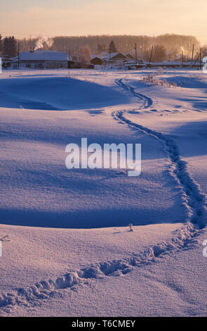 Sentier des traces dans la neige, dans l'Altaï russe village en hiver à l'heure du matin Banque D'Images