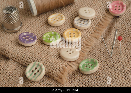 Boutons en bois avec des bandes de couleurs de couleur sur un tissu rustique, la couture Banque D'Images