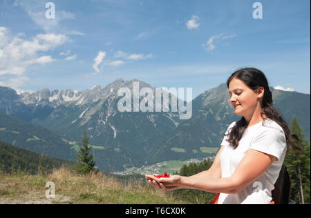 Jeune femme brune en tenue de montagne Alpes fraises sauvages dans les mains Banque D'Images