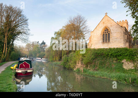 L'église sainte Croix et Canal bateau sur le canal d'oxford, au petit matin le soleil de printemps. Shipton on Cherwell, Oxfordshire, Angleterre Banque D'Images