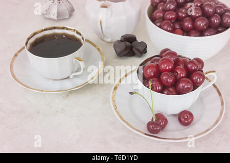 Le café et les cerises dans une tasse sur la table Banque D'Images