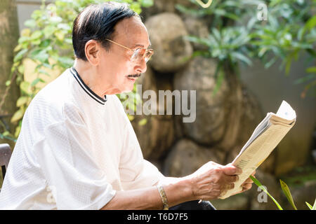 Senior man reading newspaper Banque D'Images