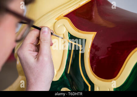 Close up of woman wearing glasses dans un atelier de peinture, de cheval de bois traditionnelle de merry-go-round. Banque D'Images