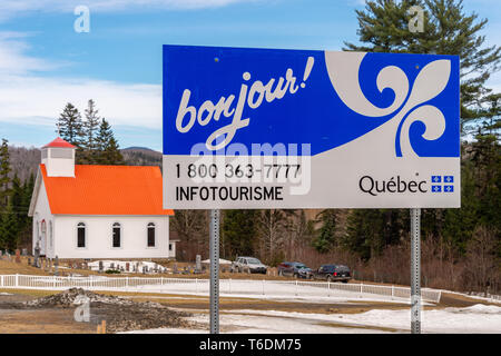 Hereford, QC, Canada - 21 Avril 2019 : Bienvenue au Québec signe en frontière USA/Canada, avec l'église anglicane All Saints en arrière-plan Banque D'Images