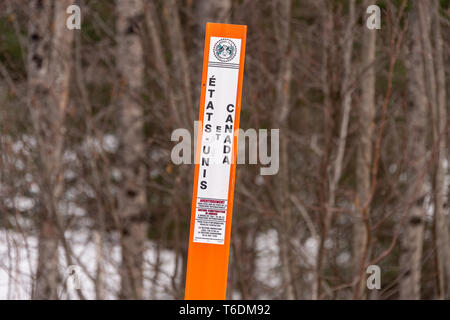 Saint-Herménégilde, QC, Canada - 21 Avril 2019 : un marqueur de frontière marque la frontière USA/Canada. Banque D'Images