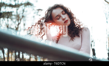 Libre d'une belle jeune femme aux cheveux bouclés - un coucher de soleil derrière elle Banque D'Images