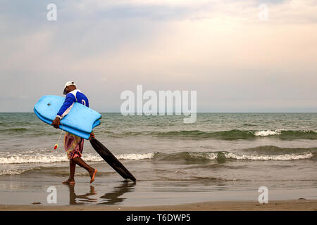 Un homme marche au travail realiser certains conseils mini simmons très tôt le matin sur une plage près de Carthagène, Colombie. Banque D'Images