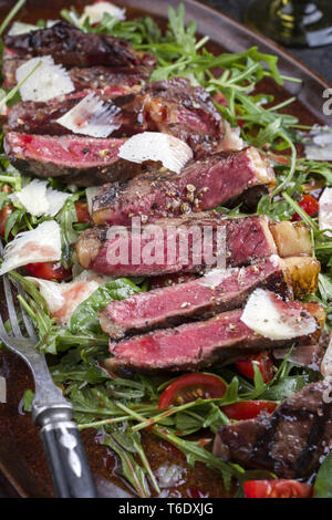 Italien traditionnel steak tagliata de parmesan et salade comme close-up sur une plaque Banque D'Images