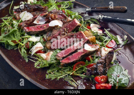 Italien traditionnel steak tagliata de parmesan et salade comme close-up sur une plaque Banque D'Images