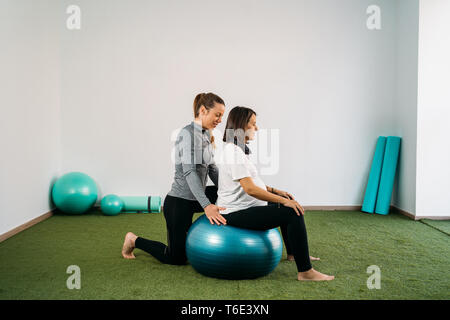 Femme enceinte faisant boule de forme physique et l'exercice de pilates avec l'entraîneur. Avenir heureux mère préparer pour l'accouchement. Banque D'Images