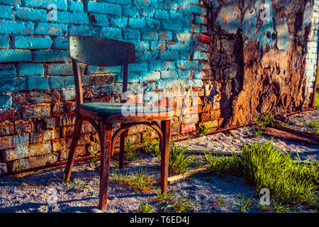 Ancienne chaise en bois debout près du mur d'une maison en ruine Banque D'Images