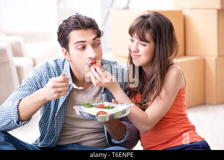 Jeune famille de manger des aliments dans nouvel appartement après déménagement dans Banque D'Images