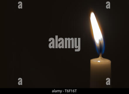 Une lumière candle burning brillamment dans l'arrière-plan noir Banque D'Images
