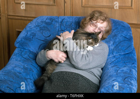 Vieille Femme dormir dans une chaise hugging a cat Banque D'Images