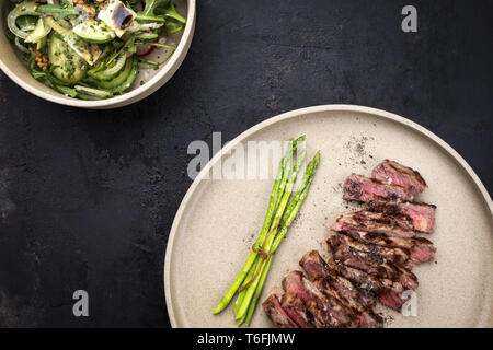 Barbecue traditionnel steak jupe en tranches avec une salade verte et asperges comme close-up sur une plaque Banque D'Images
