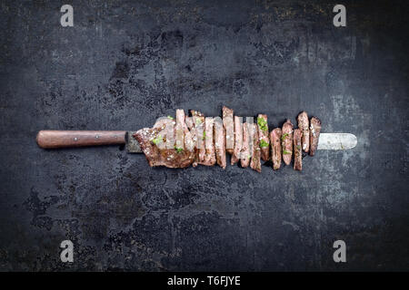 Barbecue traditionnel steak jupe tranché selon close-up sur un couteau with copy space Banque D'Images