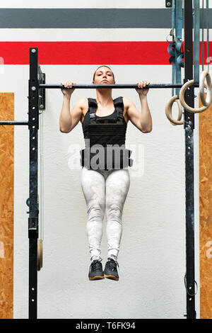 Jeune femme faisant de l'athlète-pondéré sur un bar portant une veste lourde pour renforcer les muscles de son corps dans un concept de santé et de remise en forme Banque D'Images