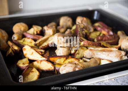 Plat à rôtir au four avec des pilons de poulet cuit et assaisonné de kumara rouge fumé le romarin, du sel de mer et poivre blanc. Banque D'Images