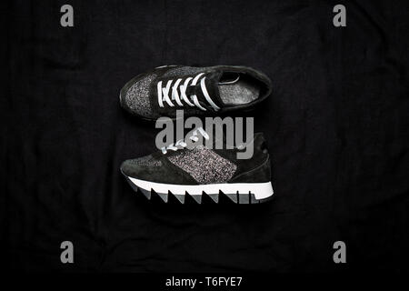 Sneakers daim noir ancienne décorée avec des paillettes d'argent sur un fond tissé noir Banque D'Images