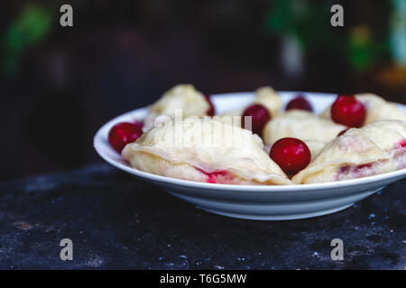 Quenelles avec les cerises dans un plat sur une sombre rétro arrière Banque D'Images