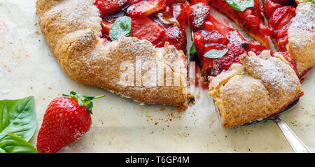 Couper des gâteaux avec des fraises et du basilic. Banque D'Images