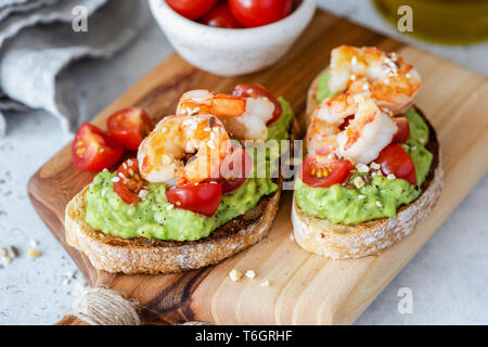 Crevettes à l'avocat bruschetta à la Tomate Cerise sur le sol en bois servant de sélection. Vue rapprochée. Apéritif ou un en-cas sains Banque D'Images