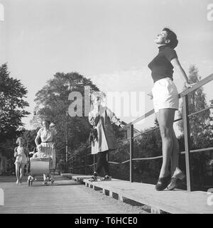 L'été 1950. Alors qu'une jeune femme portant des shorts et cavalier est posé pour le photographe une dame passe avec un enfant dans une poussette. Kristoffersson Photo ref BP39-8. Suède 1954 Banque D'Images