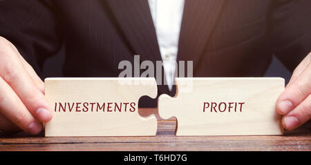 Businessman recueille des puzzles avec les mots les investissements et les bénéfices. Le retour sur investissement et capital investi. Taux de rendement. ROR. Le retour sur investissement. Prof d'affaires Banque D'Images