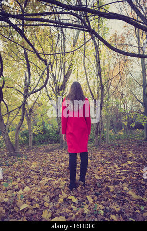 Femme toute seule dans la forêt avec un long manteau rouge, à l'écart Banque D'Images