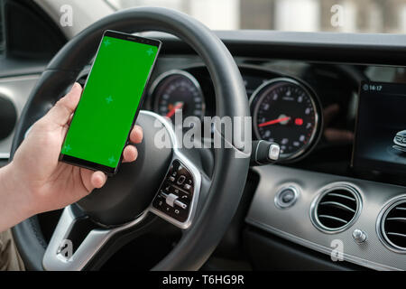 Man using smartphone sur l'arrière-plan d'un tableau de bord de voiture de luxe. Banque D'Images