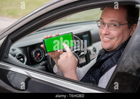 Homme d'âge moyen montre Smartphone avec écran chromakey Banque D'Images