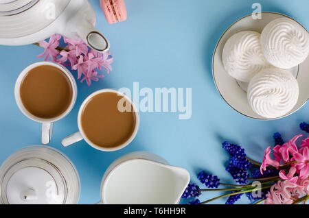 Deux tasses de café avec du lait, lait, meringues blanches sur fond bleu pastel décorées de muscari et jacinthes fleurs. Haut de la vue, télévision lay. Bre Banque D'Images