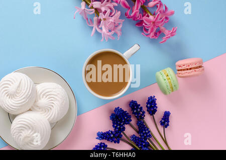 Petit-déjeuner romantique avec des meringues, macarons, pot de lait sur un fond bleu pastel décorées de muscari et jacinthes fleurs. Haut de la vue, télévision lay. Banque D'Images