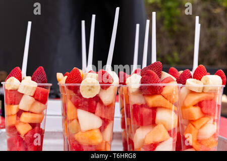 Salade de fruits disposés dans des gobelets en plastique sur un étal de marché. Banque D'Images