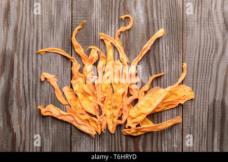 Lumineux Orange chips de carotte énoncés dans forme de langues de feu sur fond de bois. Banque D'Images