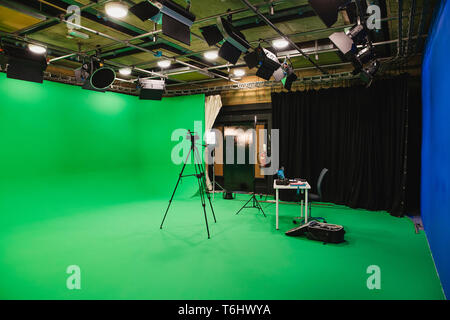 Une prise grand angle d'un studio de cinéma, un écran vert entoure le prix intérieur, un trépied se dresse au milieu de la pièce avec une caméra pour filmer Banque D'Images