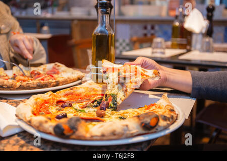 La prise de main de tranches de pizza savoureuse de la plaque dans un restaurant. Banque D'Images