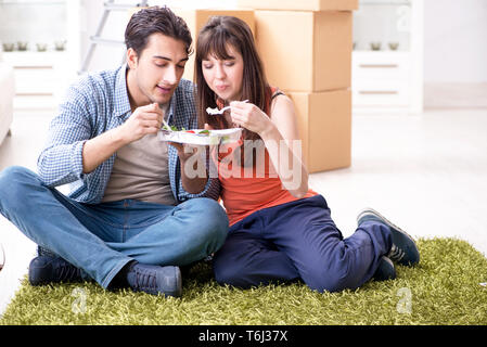Jeune famille de manger des aliments dans nouvel appartement après déménagement dans Banque D'Images