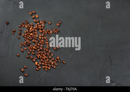 Les grains de café torréfié éparpillées sur un fond de béton vide Banque D'Images