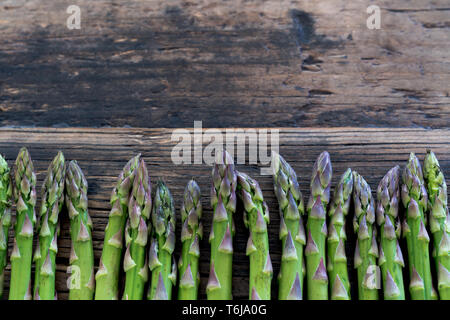 Les asperges vertes fraîches bio sur une vieille table en bois brun rustique with copy space Banque D'Images