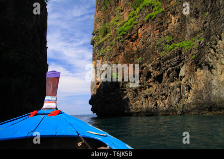 Vue sur l'arc en bois décorés de bleu bateau longtail et passage entre des murs de pierre des deux côtés sous ciel bleu avec quelques nuages cirrus - Tropical Island Banque D'Images