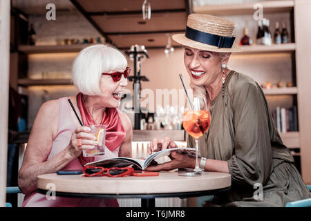 Rire de bon à hauts copines assis ensemble dans un café Banque D'Images