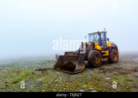 Le bulldozer jaune sur fond vert pâle dans le brouillard Banque D'Images